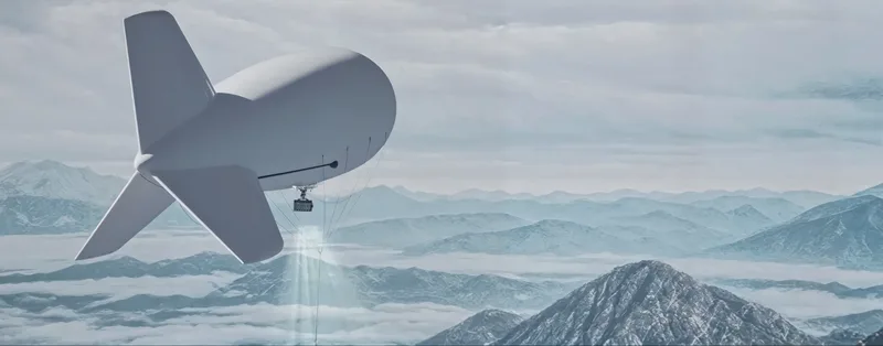 Kabelgebundener Fesselballon mit Sensornutzlast im Schwebeflug über einer schneebedeckten Gebirgslandschaft zur Luftaufklärung