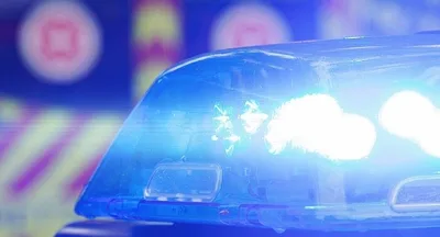 BOS:EXPO: Eingeschaltete blaue Sondersignalanlage auf dem Dach eines Einsatzfahrzeugs vor unscharfen reflektierenden Warnmarkierungen