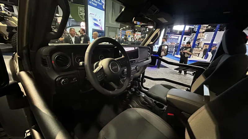 Innenraum eines Jeep-Geländefahrzeugs mit Rohrrahmentüren auf einer Wehrtechnikmesse vor Ausstellungsständen und Besuchern