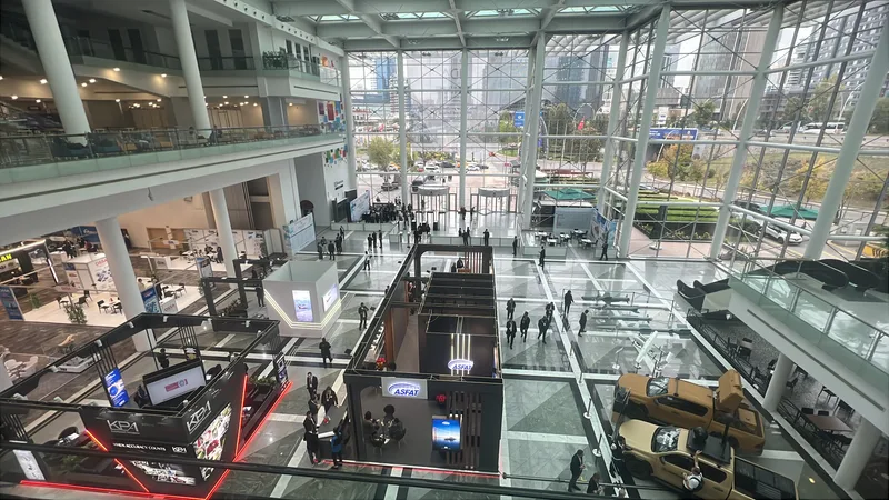 Blick von oben in das Atrium einer Rüstungsmesse mit ASFAT-Messestand, Militärfahrzeugen sowie Modellen von Flugkörpern und Drohnen