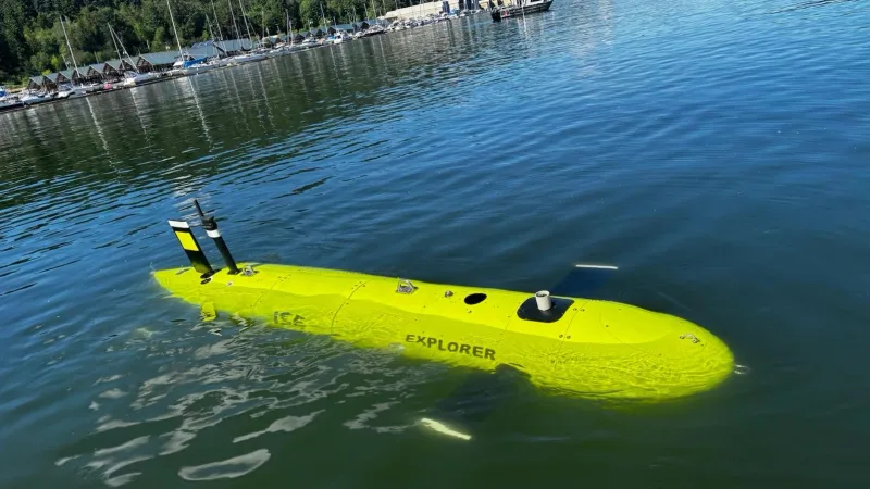 Autonomes Unterwasserfahrzeug Explorer von International Submarine Engineering an der Wasseroberfläche vor einem Küstenabschnitt