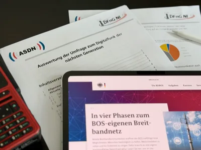 Tablet mit BDBOS-Website zum BOS-Breitbandnetz neben Dokumenten der ASDN Niedersachsen und einem Handfunkgerät für die Einsatzkommunikation.