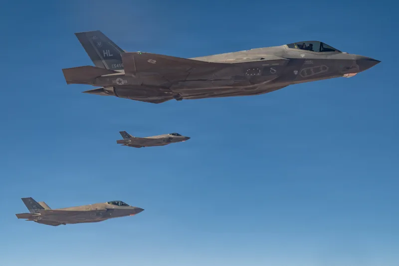 Drei Lockheed Martin F-35A Lightning II der US Air Force mit HL-Leitwerkskennung fliegen in Formation vor klarem Himmel