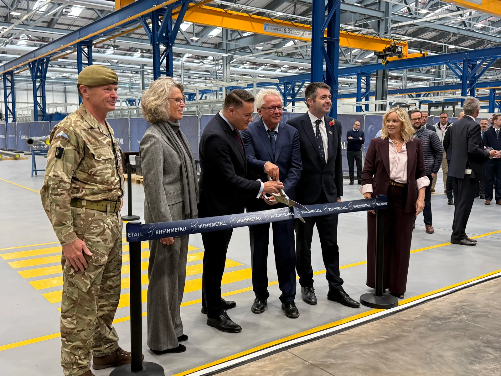 Vertreter von Rheinmetall und britische Militärangehörige durchschneiden bei der Eröffnung einer neuen Produktionshalle ein Band