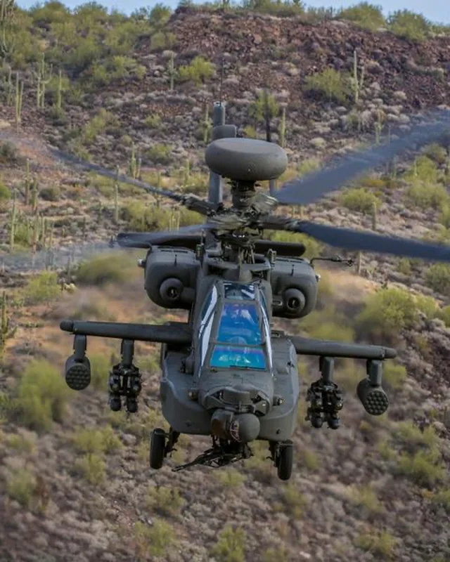 Boeing AH-64 Apache Kampfhubschrauber mit Mastradar und Bewaffnung im Tiefflug über aridem Gelände
