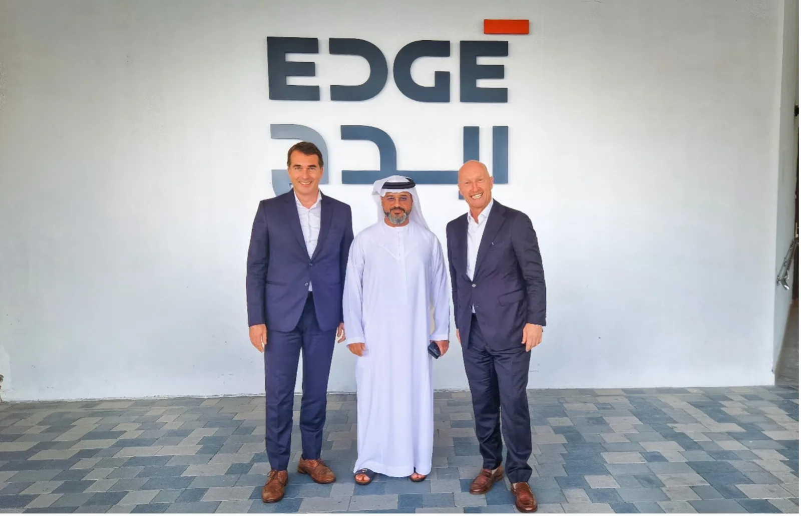 Drei Unternehmensvertreter vor dem Logo der EDGE Group bei einer Kooperation mit SFC Energy in den Vereinigten Arabischen Emiraten