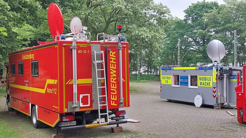 Einsatzleitwagen der Feuerwehr auf MAN-Fahrgestell mit Gimaex-Aufbau und mobile Polizeiwache mit Satellitenantennen auf einem Platz