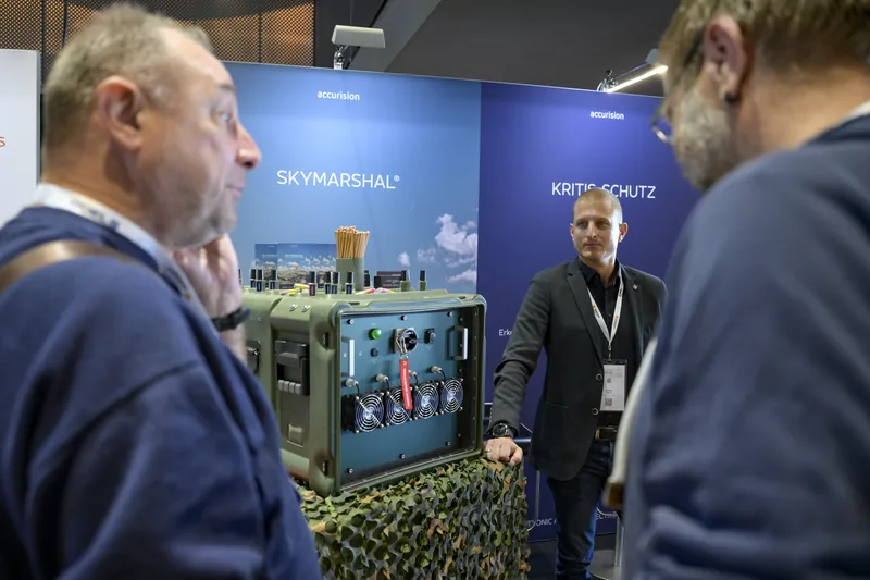 Firmenvertreter von Accurision erläutert Fachbesuchern das modulare Schutzsystem Skymarshal an einem Messestand
